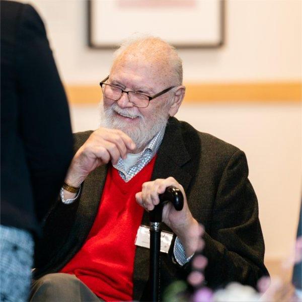 Vernon Ohlman seated with hand on cane laughing